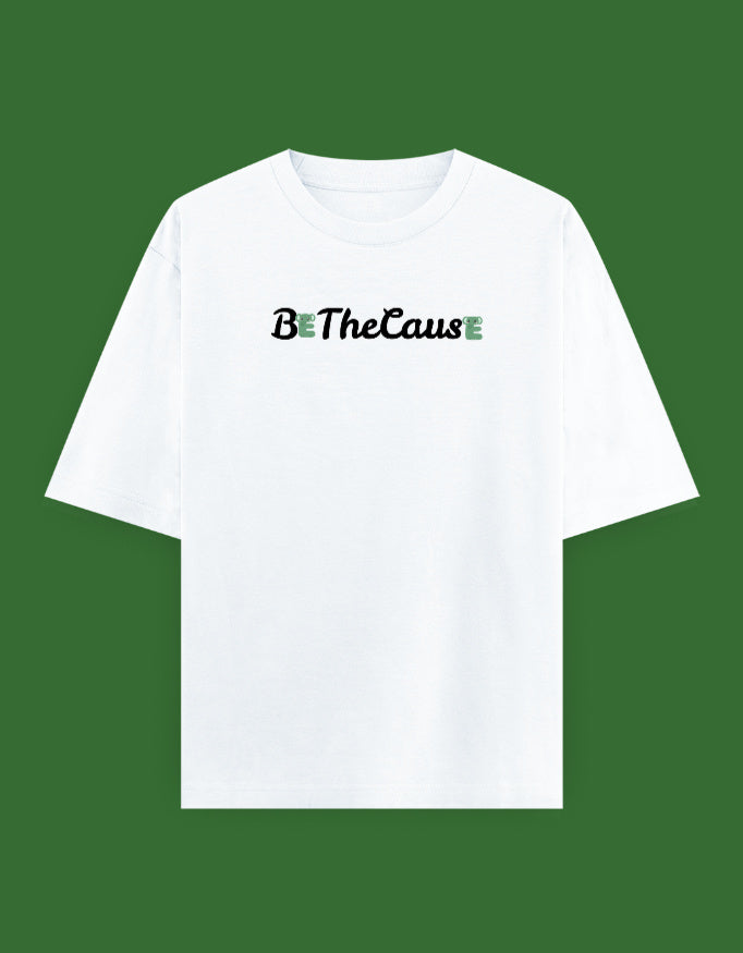 A white short-sleeve crewneck t-shirt with the text 'Be The CausE' printed across the chest in black script and green block letters, displayed against a solid dark green background.