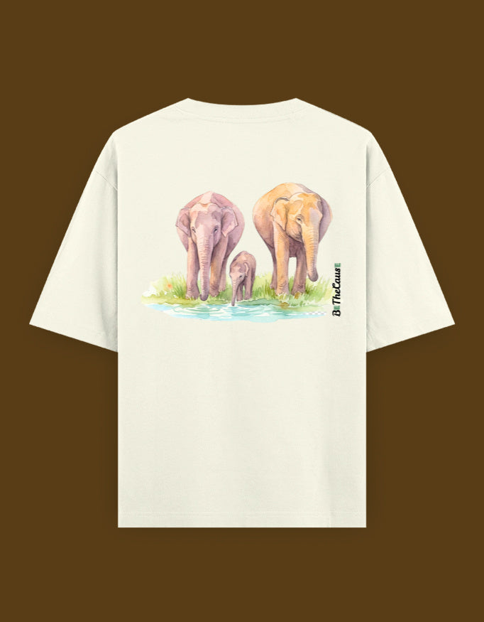 An off-white short-sleeve t-shirt with a watercolor graphic of three elephants standing in water on the back, displayed against a solid dark brown background.
