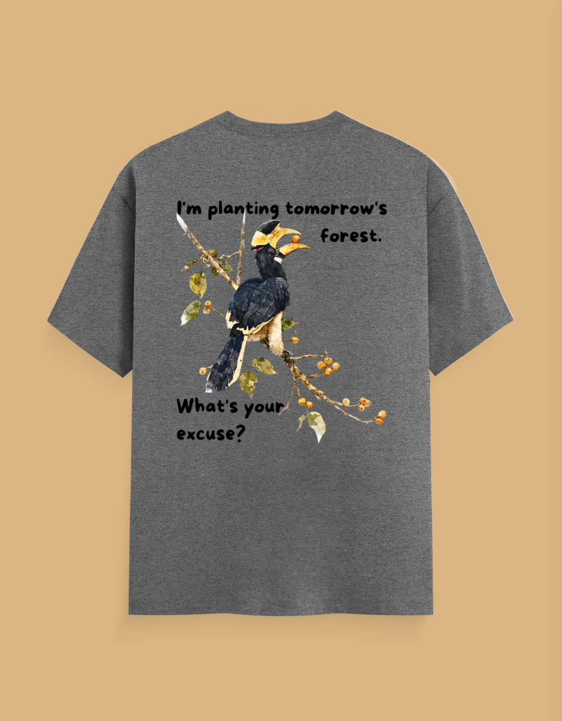 A heather gray short-sleeve t-shirt with a graphic of a hornbill bird on a branch, featuring the text 'I'm planting tomorrow's forest. What's your excuse?' on a solid tan background.