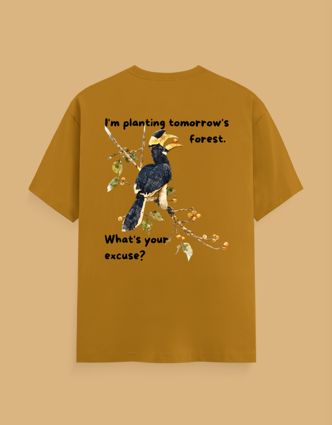 A mustard yellow t-shirt with a graphic of a hornbill bird on a branch, featuring the text 'I'm planting tomorrow's forest. What's your excuse?' on a solid beige background.