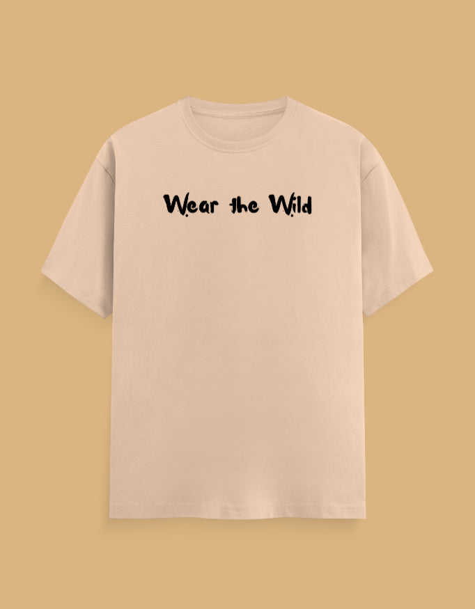A light beige short-sleeve t-shirt with the phrase 'Wear the Wild' printed in black across the chest, displayed against a solid tan background.